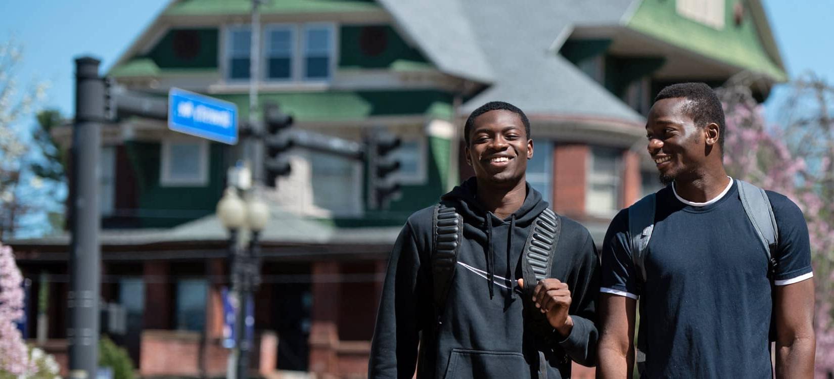 2 UB students laughing and walking on campus